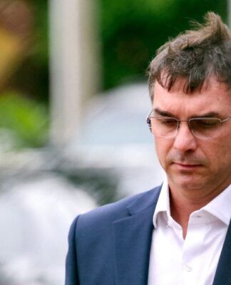 Flávio Bolsonaro, de paletó e óculos de grau, após conceder entrevista na rua