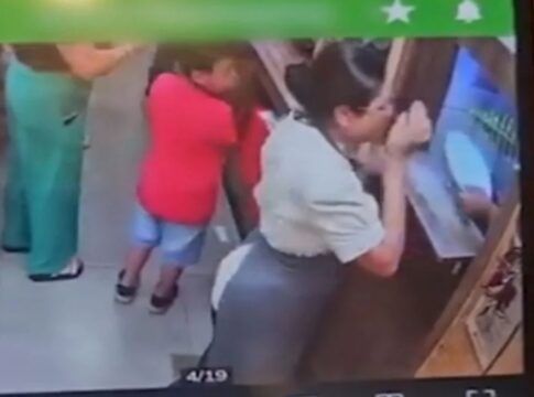 Foto da tela de um celular mostrando o instante em que a funcionária é golpeada no rosto