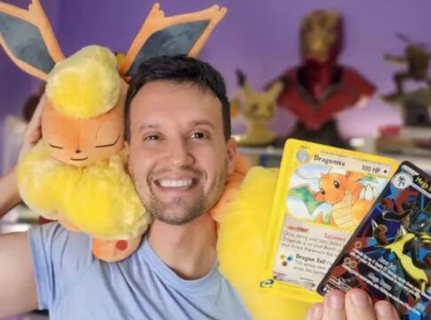 Homem posando para a câmera com pelúcias e cartas de Pokémon