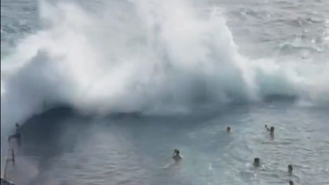 Momento em que uma onda gigante se choca contra a estrutura de uma piscina natural