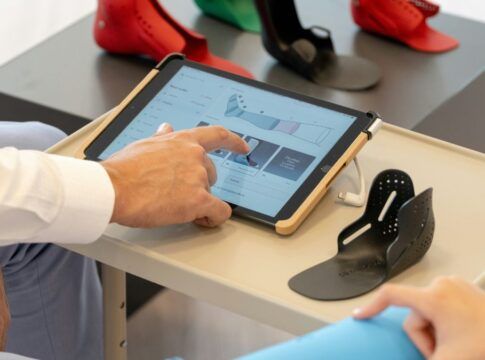 Close dos braços de dois funcionários de uma empresa, com um deles mexendo na tela de um tablet