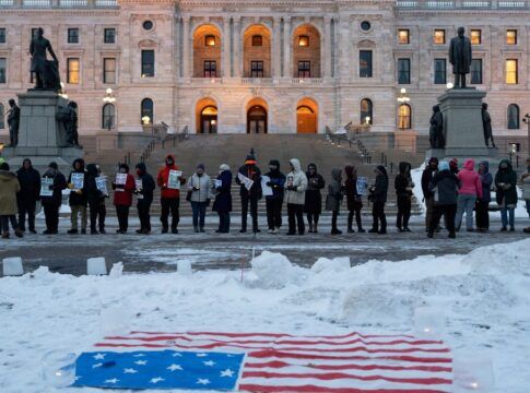 Manifestantes participam de vigília à luz de velas em frente ao Capitólio Estadual em St. Paul, Minnesota, com a bandeira dos EUA colocada sobre a neve