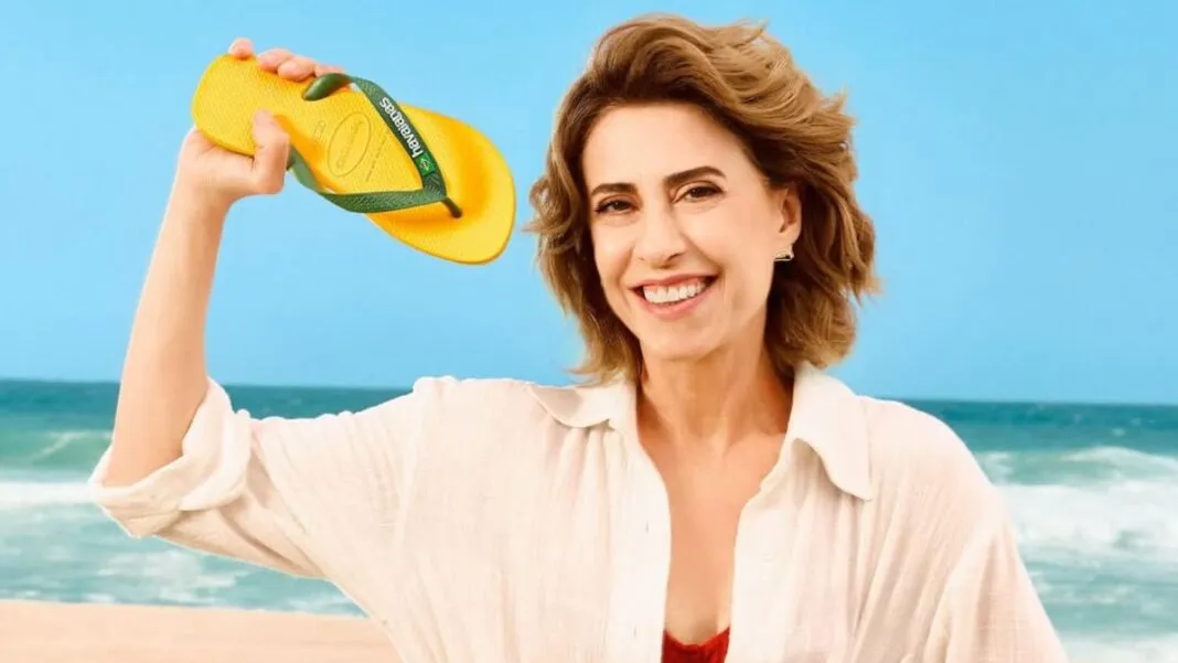 Atriz Fernanda Torres segura com a mão uma Havaianas de cor amarela e verde
