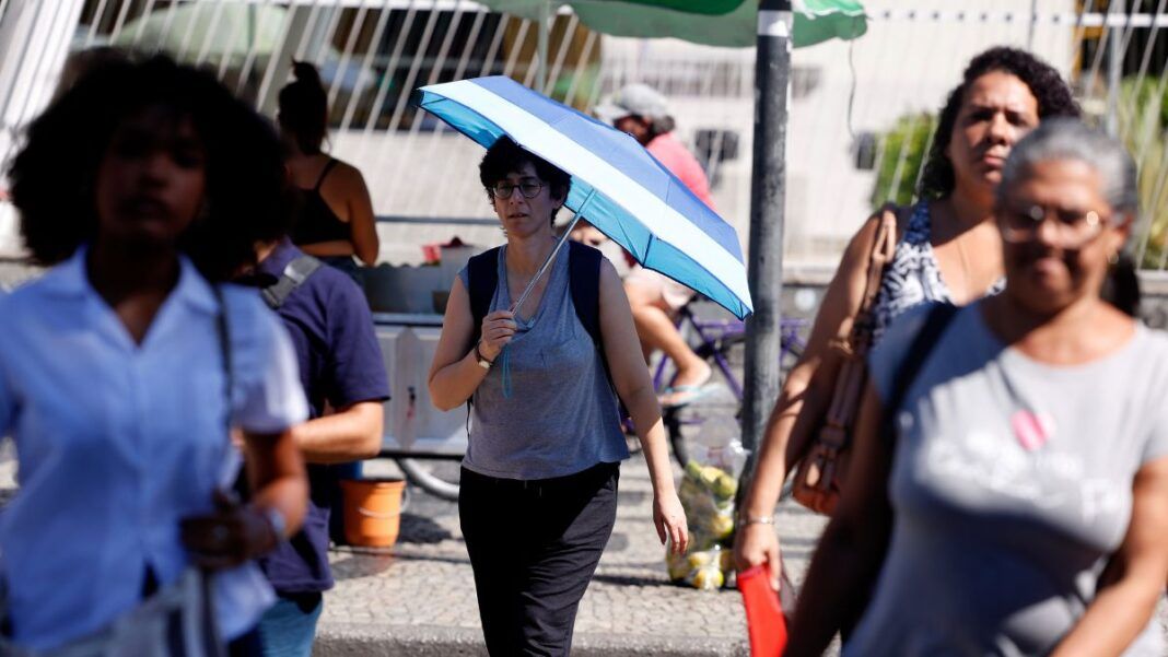 Pessoas com calor nas ruas do Rio, uma delas com uma sombrinha