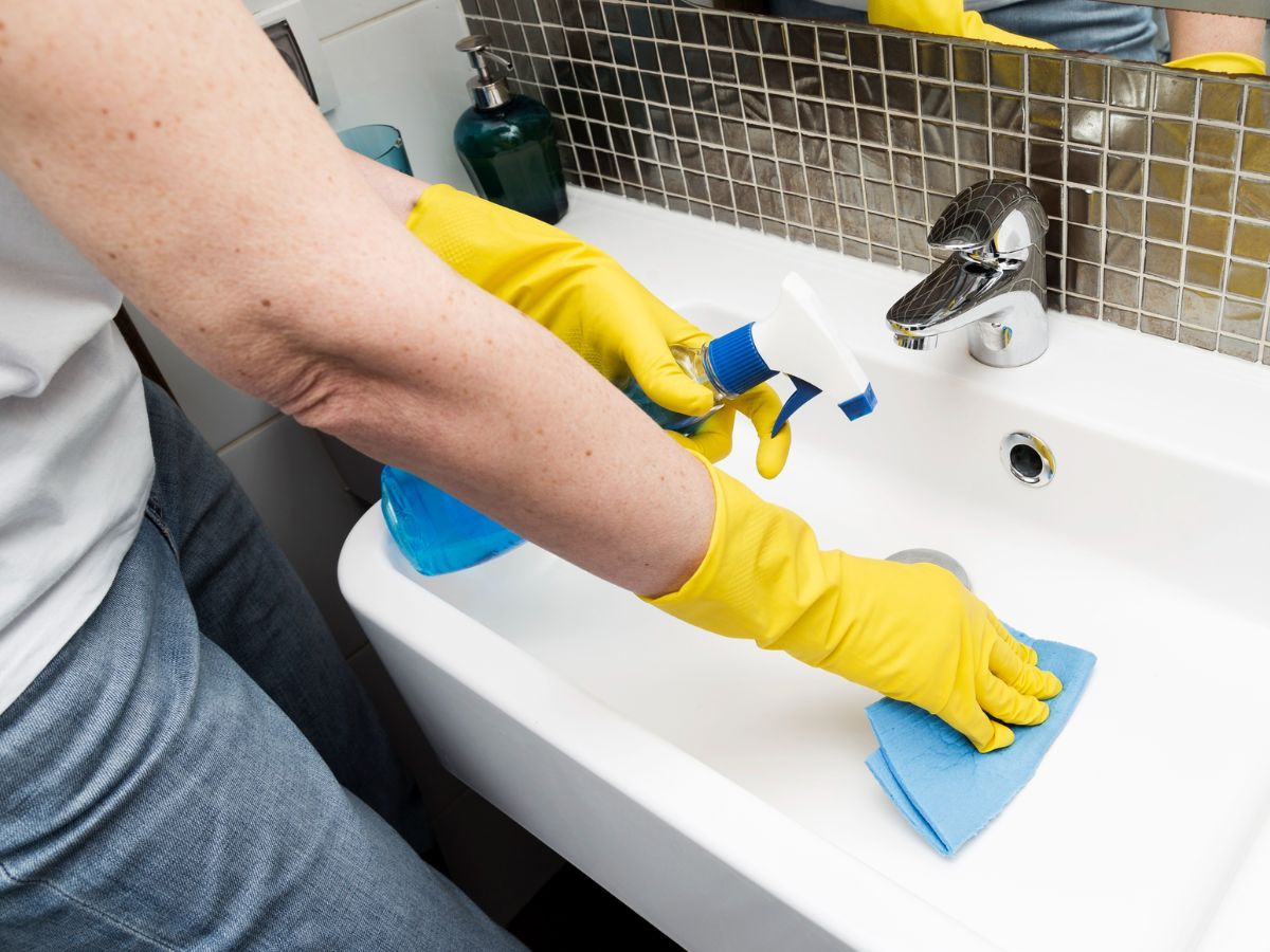 Homem limpando a pia do banheiro 