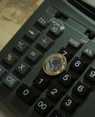 Imagem de uma moeda de um real colocada sobre uma calculadora