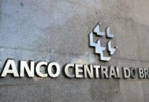 A imagem é um close-up que foca na parte central da fachada externa do edifício do Banco Central do Brasil, destacando o nome da instituição e seu símbolo em metal.