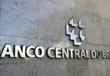 A imagem é um close-up que foca na parte central da fachada externa do edifício do Banco Central do Brasil, destacando o nome da instituição e seu símbolo em metal.