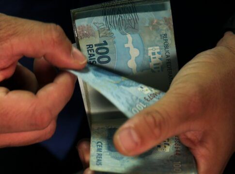 notas de 100 reais nas mãos de uma pessoa