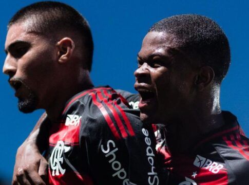 A foto em plano médio captura dois jogadores de futebol do time do Flamengo celebrando um momento de gol ou vitória com grande intensidade emocional.