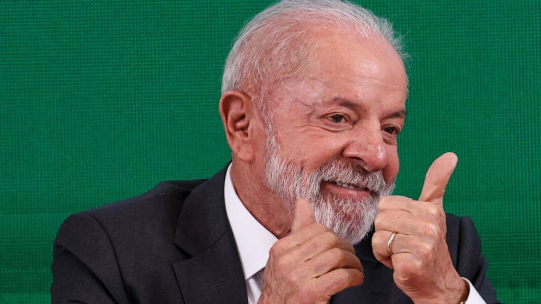 A foto mostra um plano médio do presidente Luiz Inácio Lula da Silva, que está sorrindo e gesticulando com as duas mãos em um sinal de aprovação (