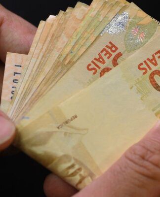 Duas mãos contam notas de 50 reais