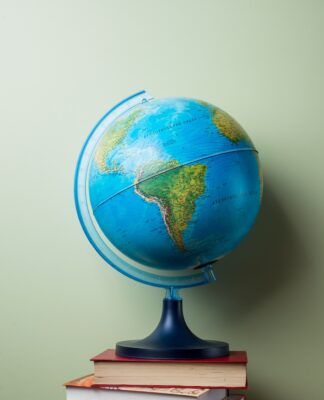 livros empilhados e um globo terrestre no topo