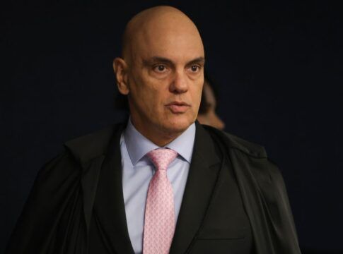 A imagem é um plano médio que foca no ministro do Supremo Tribunal Federal (STF), Alexandre de Moraes, em um ambiente interno e formal.