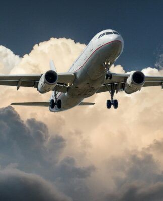 avião branco no céu com nuvens brancas ao fundo e céu azul
