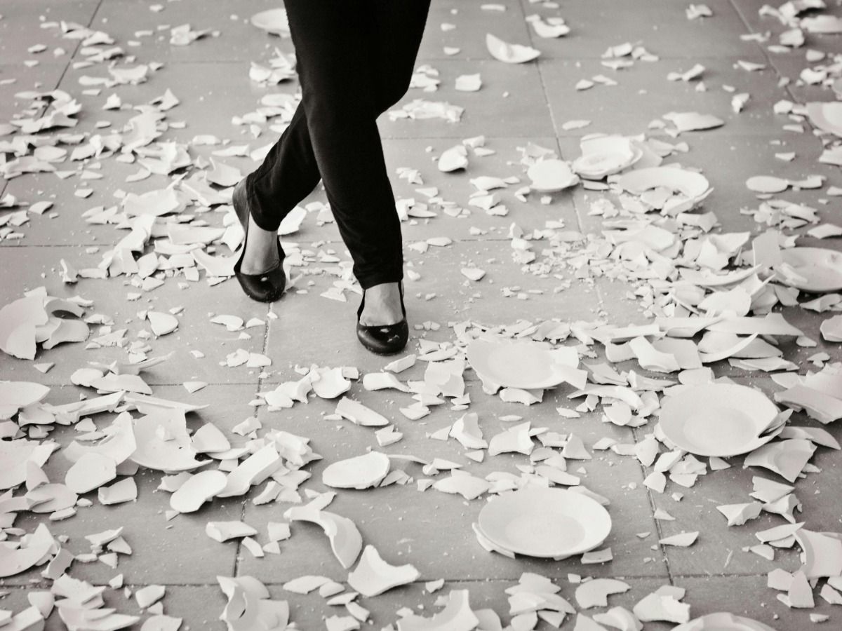 Pessoa passando por pratos quebrados no chão