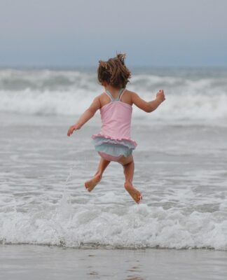 Criança pulando onda no mar