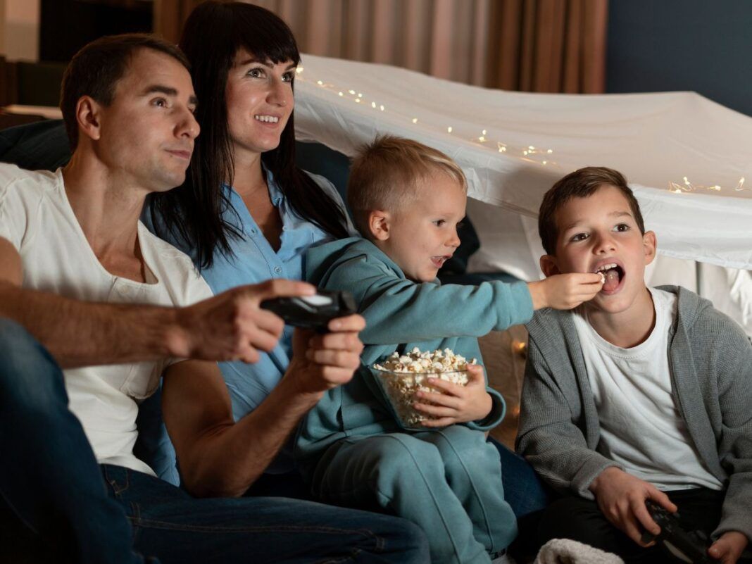 Em imagem ilustrativas família está pronta para assistir um filme em casa