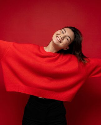 Adolescente rindo com uma blusa vermelha.