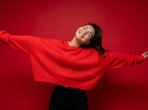 Adolescente rindo com uma blusa vermelha.