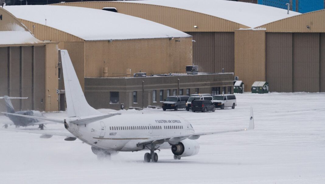Vans que transportam detidos com destino a um voo de deportação aguardam enquanto um avião fretado taxiava em direção à Signature Aviation no Aeroporto Internacional de Minneapolis–St. Paul