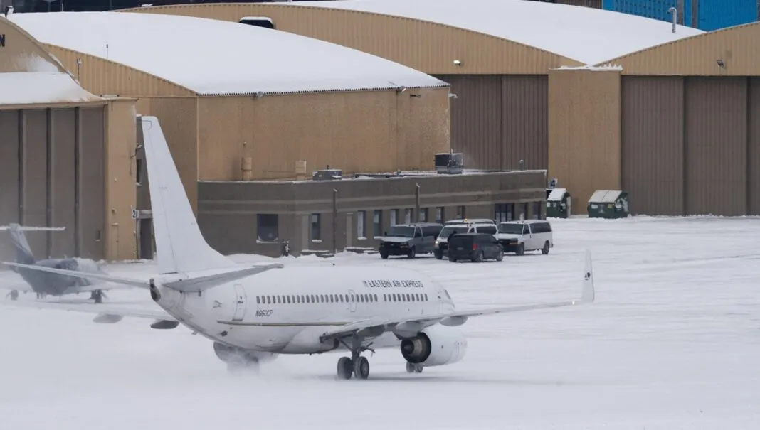 Vans que transportam detidos com destino a um voo de deportação aguardam enquanto um avião fretado taxiava em direção à Signature Aviation no Aeroporto Internacional de Minneapolis–St. Paul