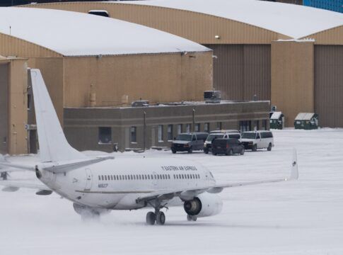 Vans que transportam detidos com destino a um voo de deportação aguardam enquanto um avião fretado taxiava em direção à Signature Aviation no Aeroporto Internacional de Minneapolis–St. Paul