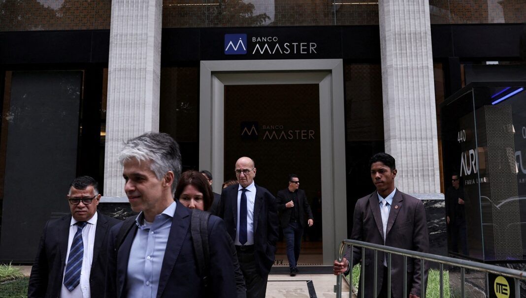 Um segurança segura uma grade enquanto pessoas deixam o Banco Master após a prisão do acionista controlador da instituição, Daniel Vorcaro