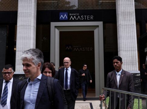 Um segurança segura uma grade enquanto pessoas deixam o Banco Master após a prisão do acionista controlador da instituição, Daniel Vorcaro