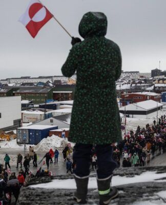 Mulher acena com uma bandeira da Groenlândia durante um protesto contra a exigência do presidente dos Estados Unidos, Donald Trump, de que a ilha no Ártico seja cedida aos EUA