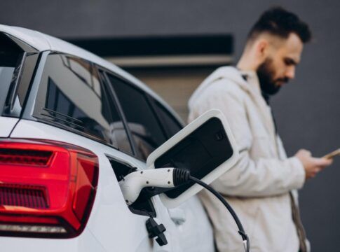 Homem carregando carro elétrico perto da casa