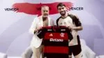 Paquetá segura a camisa do Flamengo ao lado de José Boto