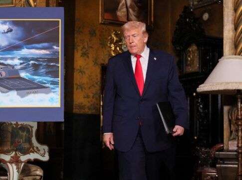 O presidente dos Estados Unidos, Donald Trump, passa por uma imagem de projeção do navio da “Classe Trump”, o USS Deifant, em Mar-a-Lago, em Palm Beach, na Flórida