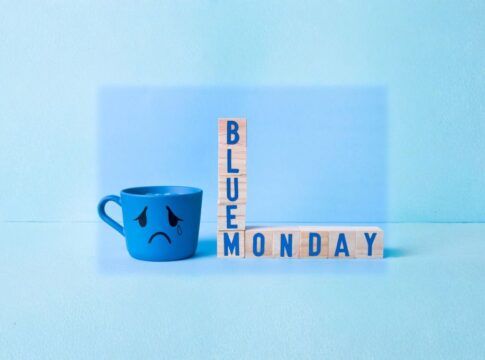 Imagem conceitual de Blue Monday, com caneca azul com cara triste e brinquedo de montar formando a palavra