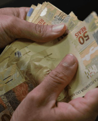 Duas mãos contam notas de 50 reais