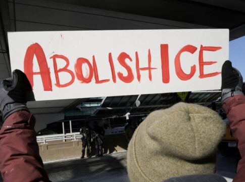 Pessoa segura um cartaz escrito: 