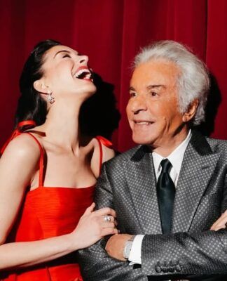 Anne Hathaway ao lado de Valentino Garavani, usando vestido vermelho da marca do estilista