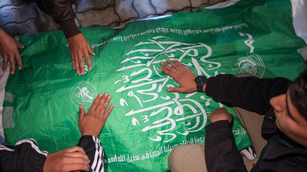 Homens com as mãos sobre uma bandeira do Hamas