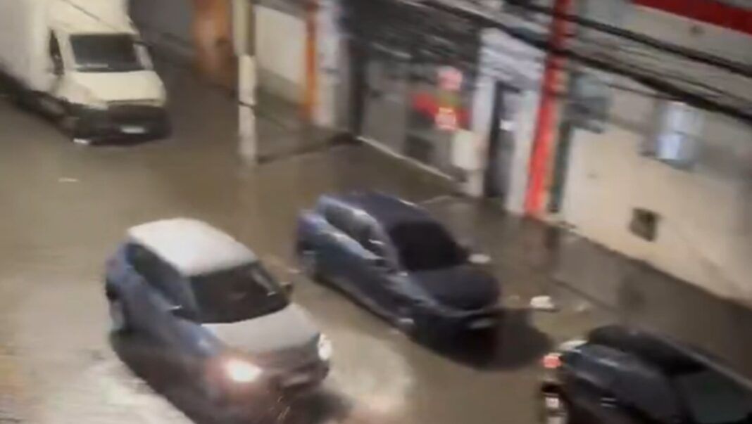 Carros passam por rua alagada em São Paulo