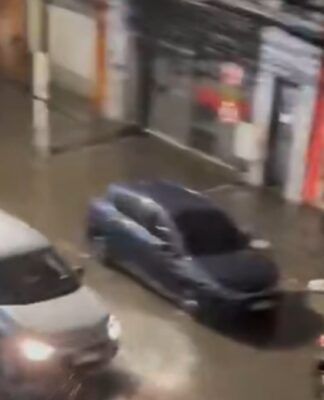 Carros passam por rua alagada em São Paulo