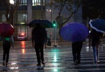 Pessoas usam guarda-chuva durante chuva no centro da cidade