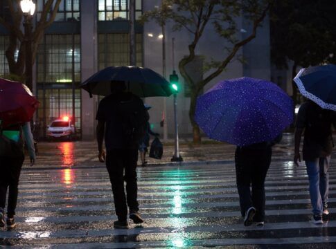 Pessoas usam guarda-chuva durante chuva no centro da cidade