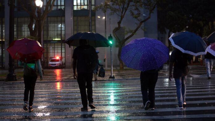 Pessoas usam guarda-chuva durante chuva no centro da cidade