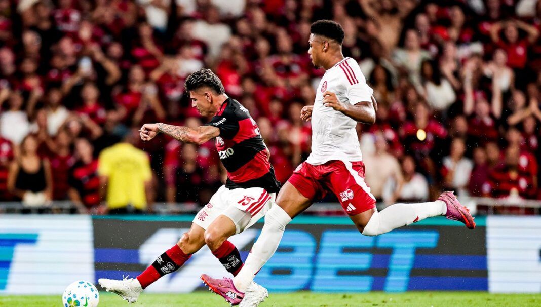 Jogador do Flamengo em disputa de bola com atleta do Inter