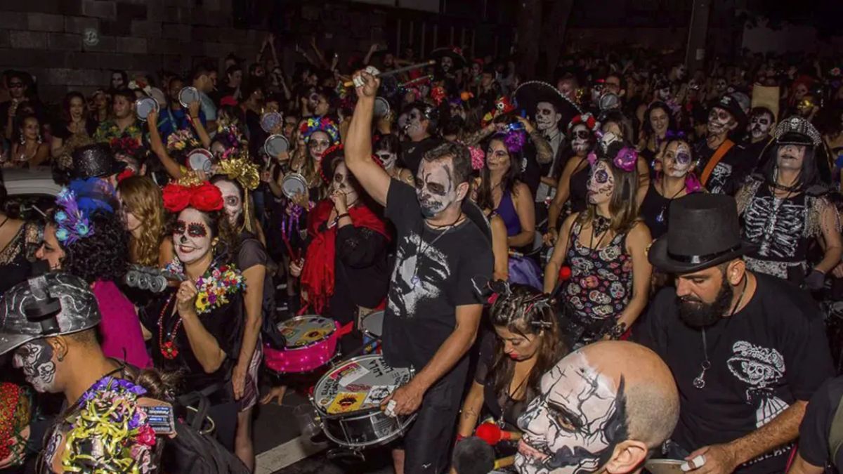 Pessoas tocando no Bloco Fúnebre de BH, todos vestidos de caveira, na rua, durante a noite