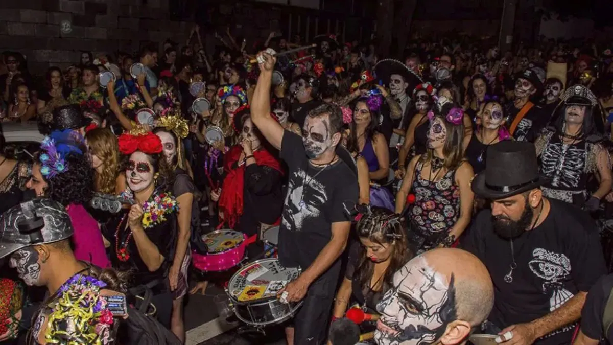 Pessoas tocando no Bloco Fúnebre de BH, todos vestidos de caveira, na rua, durante a noite