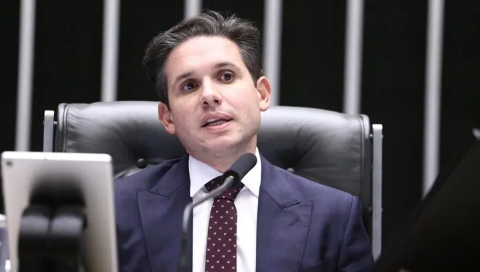 Hugo Motta sentado na cadeira de presidente da Câmara