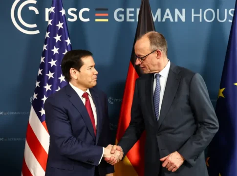 Dois homens apertam mãos em frente às bandeiras de Estados Unidos Alemanha: Marco Rubio e Friedrich Merz