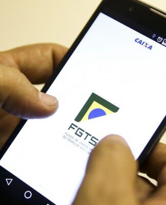 Mão segura celular com aplicativo do FGTS na tela
