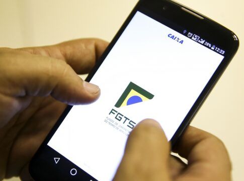 Mão segura celular com aplicativo do FGTS na tela